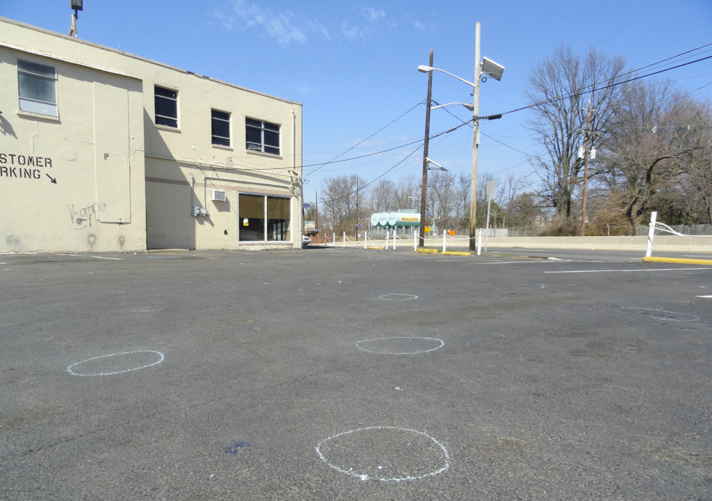 Chalk circles outline gunshots in the parking lot of Pitts Auto. Credit: Matt Skoufalos.